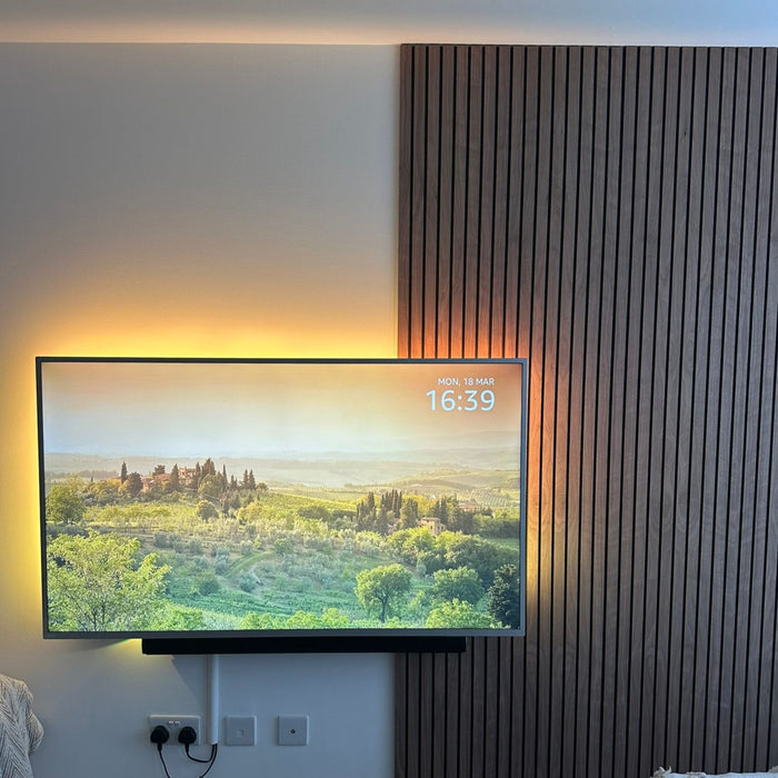 Beautiful walnut slat wall panels enhance TV area ambiance, accented by vibrant LED lights for a modern, stylish look.